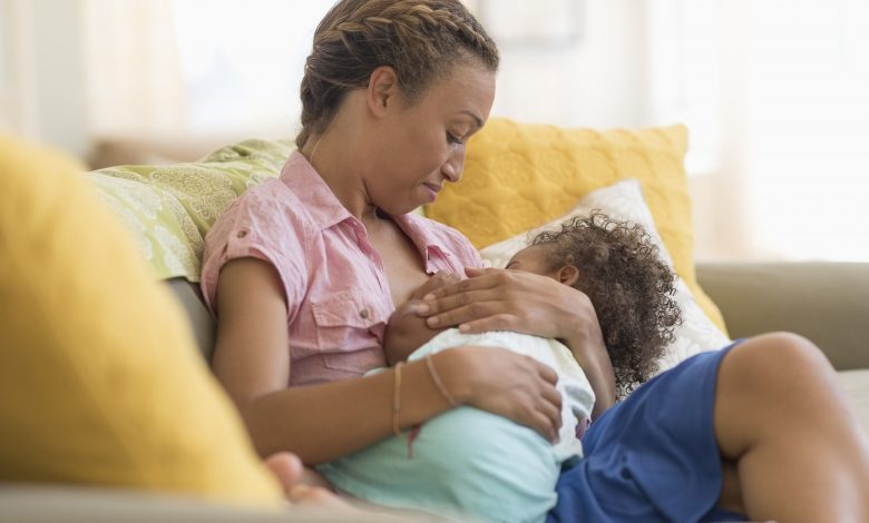 mixed race mother nursing daughter in living room 526296725 596fda74aad52b001128f3c0